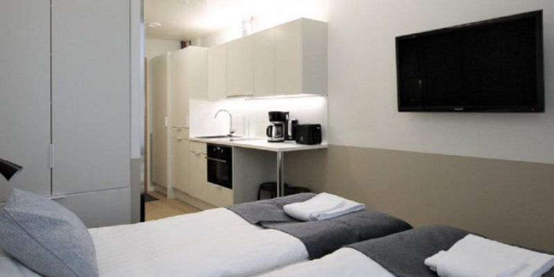 Forenomin huoneisto, jossa vaalea keittiöpiste ja sängyt