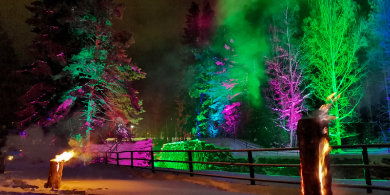 Valotaidetta Taipaleen kanavalla. Kuvassa tuliteoksia sekä vihreän ja liilan sävyyn värjäytyneitä puita.