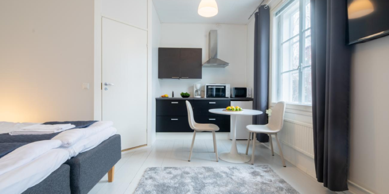 Vanhan Postitalon huoneisto, jossa tumma keittiöpiste ja ruokapöytä ikkunan edessä. 