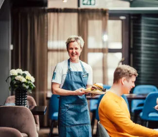 Hymyilevä tarjoilija burgerin kanssa. 
