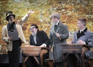 Kohtaus Varkauden teatterin Savonmuan piätön historia -revyystä, jossa ihmisiä luokkahuoneessa.