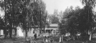 Mustavalkokuva Tyyskän pihapiiristä, jossa ihmisiä