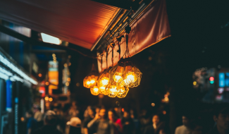 Pimeässä valaistu katu, jossa taustalla hämärästi näkyviä ihmisiä