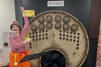 Klovnipukuinen nainen Lasten tehtaassa kattilapajan edessä