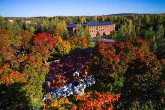 Syksyinen ilmakuva Vanhasta Varkaudessa,kuvassa voimakkaat ruskan värit, vanhaa puutalokantaa ja taustalla Varkauden museokeskus Konsti