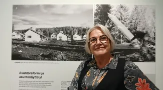 Vaaleahiuksinen nainen seisoo näyttelytaulun edessä
